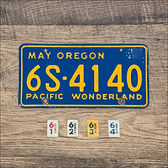 A single original 1961-1964 Oregon Pacific Wonderland license plate with optional year stickers arranged below it.